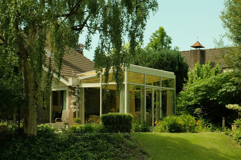 Modern sunroom attached to a house surrounded by trees.